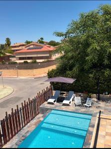 a swimming pool with two lounge chairs and a fence at Solea Alcayna in La Alcayna
