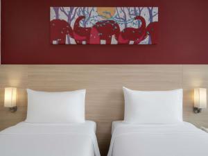 two beds in a room with a painting on the wall at ibis Bangkok Siam in Bangkok