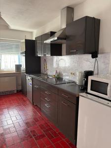 a kitchen with stainless steel appliances and a red tile floor at Ferienwohnung Freudenberg in Freudenberg am Main