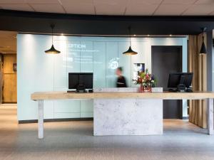 a lobby with a reception desk with two monitors on it at ibis Rotterdam City Centre in Rotterdam
