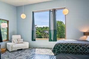 a bedroom with a bed and a chair and a window at The Crag On the Acadia National Park Border - Deck, Fire Pit, Steps to Trails in Otter Creek