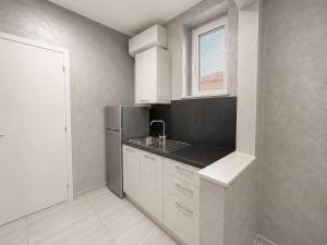 a kitchen with white cabinets and a stainless steel refrigerator at Apartment Federico in Melfi