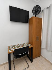 a desk with a chair and a fan on a wall at Quarto Hokkaido na Sakura House in Indaiatuba