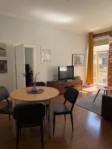a living room with a table and chairs and a television at Maironis - Spacious Apartment in the Heart of Kaunas in Kaunas
