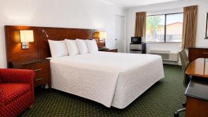 a hotel room with a large bed and a red chair at Royal Inn Hotel in Royal Palm Beach