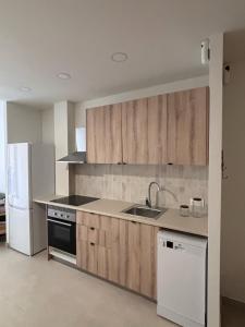 a kitchen with wooden cabinets and a sink and a refrigerator at APARTAMENTO LEPANTO in Almazora