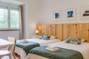 a room with two beds and a table and a table at Home Out Rooms & Apartments in Lisbon