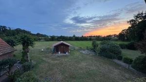 a small shed in a field with a sunset in the background at Kramerhof in Groß Fredenbeck