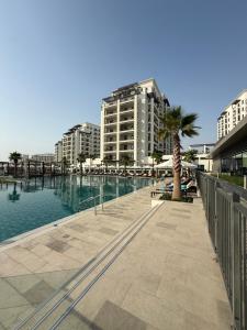 a swimming pool with a palm tree and buildings at Yas island Golf collections in Abu Dhabi
