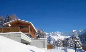 a log cabin in the snow with mountains in the background at Bed and Breakfast Raschainas Lenzerheide in Sporz +48 photos