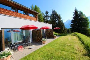 a patio with red umbrellas next to a building at Bed and Breakfast Raschainas Lenzerheide in Sporz
