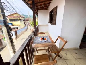 a table and chairs on a balcony with a plate of food at Reis Family Paraty - Suíte Privativa Nova e Funcional com Varanda in Paraty