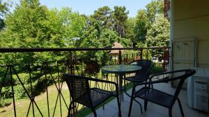 a balcony with three chairs and a table on a porch at Villa Palazzo Apartments in Siófok