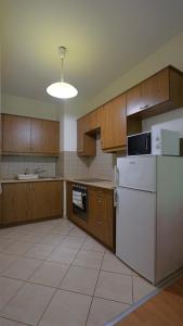 a kitchen with a white refrigerator and wooden cabinets at Villa Palazzo Apartments in Siófok