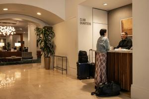 a woman standing at a counter in a hotel lobby at Club Quarters Hotel Downtown, Houston in Houston