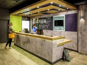 a woman standing in front of a reception desk at ibis budget Hamburg City in Hamburg