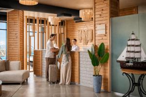 a man and woman standing at a counter with luggage at Azur White Resort Ras El Hekma in Zāwiyat al ‘Awwāmah +96 photos