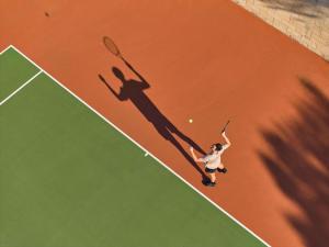 a man serving a tennis ball on a tennis court at Pullman Bunker Bay Resort Margaret River in Dunsborough
