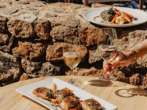 two glasses of wine and a plate of food on a table at Pullman Bunker Bay Resort Margaret River in Dunsborough