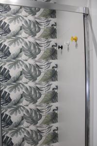 a shower curtain with a leafy wallpaper in a bathroom at Los Llanos Loft & Suites in Manzanilla