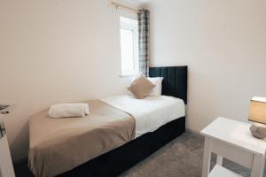a small bedroom with a bed with a window at Dinorben Retreat in Amlwch