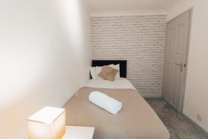 a small bedroom with a bed with a white brick wall at Dinorben Retreat in Amlwch