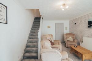 a living room with chairs and a staircase at Dinorben Retreat in Amlwch +3 photos
