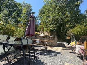 a patio with a table and an umbrella and chairs at Vue Du Vallon in Bersac-sur-Rivalier