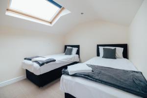 two twin beds in a room with a window at The Welsh Welcome in Pen-y-groes