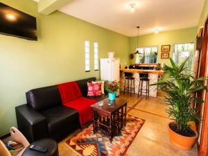 a living room with a black couch and a kitchen at Villa Pella - Chalé Tulipa- com café manhã in Brumadinho