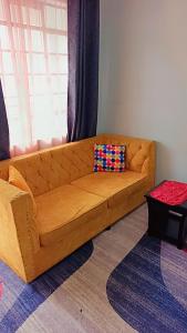 a brown couch in a living room with a window at Amaziah apartment Mimyhomes in Nairobi