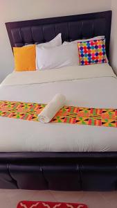 a bed with a black headboard with a colorful blanket at Amaziah apartment Mimyhomes in Nairobi