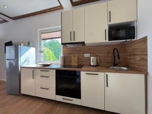 a kitchen with white cabinets and a sink and a refrigerator at Apartman Bor in Kiseljak