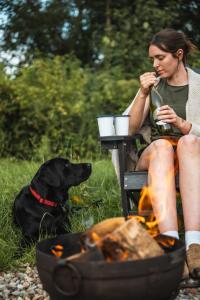 a woman sitting next to a fire with a dog at Adhara in Tarporley +14 photos