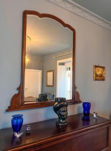 a mirror on top of a wooden table with blue vases at B&B Dàmur in Piazza Armerina