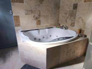 a bath tub in a bathroom with a tile wall at Apocalypse Love Room in Vianne +6 photos