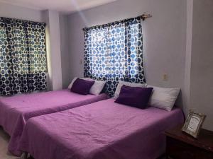 two beds in a room with purple sheets and a window at Hotel Cielo Huasteco in Ciudad Valles