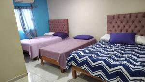 two beds in a room with violet and purple at Hotel Cielo Huasteco in Ciudad Valles