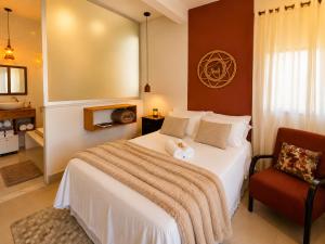 a bedroom with a white bed and a chair at Villa Pella - Chalé Rosa- hidro e café manhã in Brumadinho