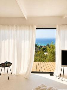 a room with a large window with a view of the ocean at THE HILL Suite in Ialysos +6 photos
