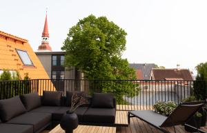 a patio with a couch and chairs on a balcony at Jannseni Premium Penthouse I Sauna I Free Parking in Pärnu