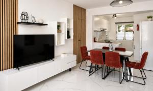 a living room with a television and a table with red chairs at Nerina Townhouse By Staycom in Paphos
