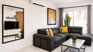 a living room with a black couch and a mirror at Nerina Townhouse By Staycom in Paphos