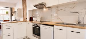 a kitchen with white cabinets and a sink at Nerina Townhouse By Staycom in Paphos +16 photos