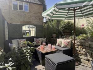 a patio with a table and an umbrella at Wind in the Willows Moreton in Marsh in Moreton in Marsh