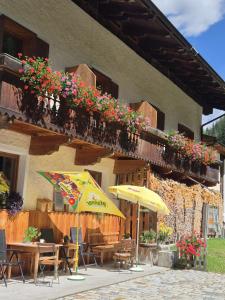 a building with tables and chairs and a balcony with flowers at Bad Kalkstein in Innervillgraten