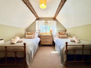 a attic bedroom with two beds and a window at Wind in the Willows Moreton in Marsh in Moreton in Marsh