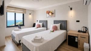 two beds in a room with a view of the ocean at Iotape Hotel Antalya in Işıklı +35 photos