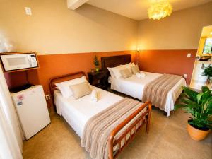 a hotel room with two beds and a refrigerator at Villa Pella - Chalé Cravo- café da manhã in Brumadinho +8 photos