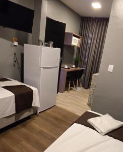 a room with two beds and a white refrigerator at FLATS MELO unimontes in Montes Claros